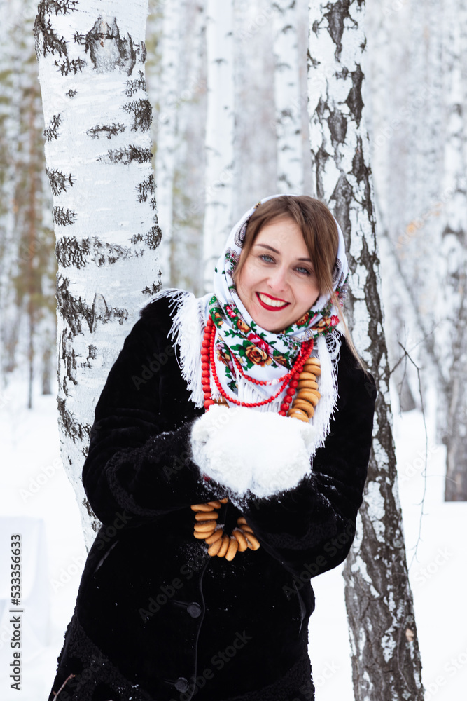 A girl in a winter forest. A beautiful woman in a fur coat at a covered table among the birches A girl in a winter forest. A beautiful woman in a fur coat at a covered table among the birches