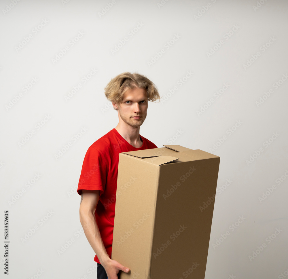 Portrait of a happy young delivery man in red uniform standing with parcel post box isolated over white background. Portrait of a happy young delivery man in red uniform standing with parcel post box isolated over white background.