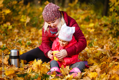 Hello autumn. smiling young mother and daughter in hats outdoors in the city park in autumn having fun time.