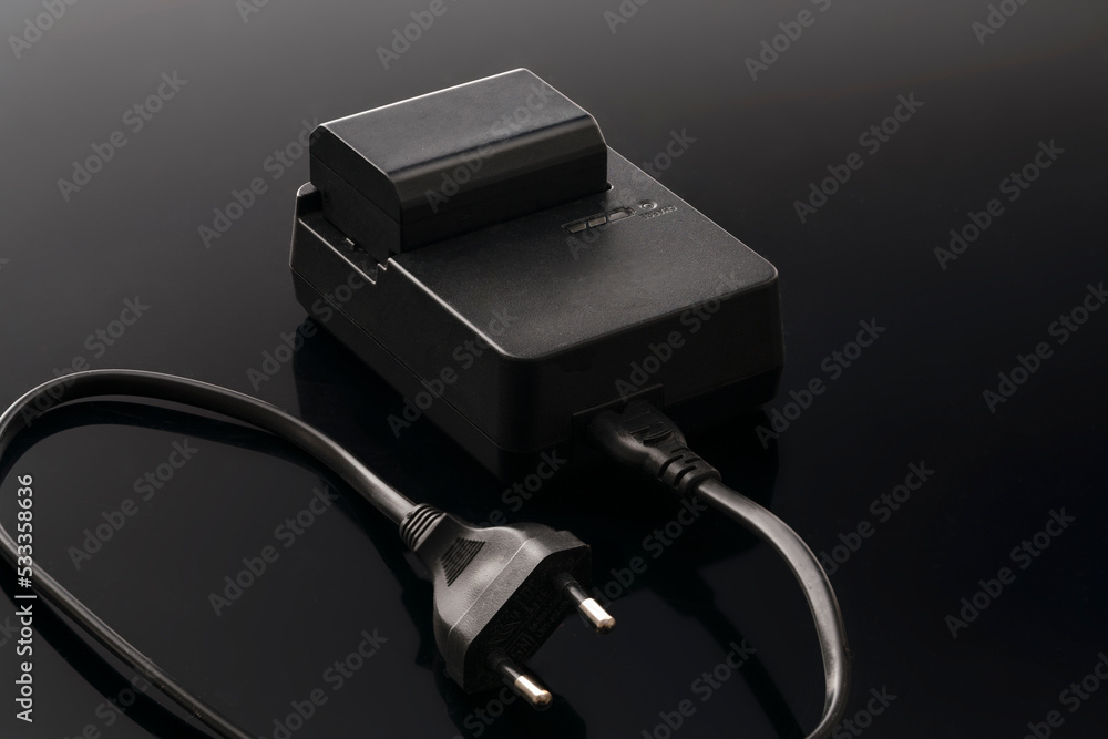 the charger and battery for the camera and household appliances are black on a dark background the charger and battery for the camera and household appliances are black on a dark background