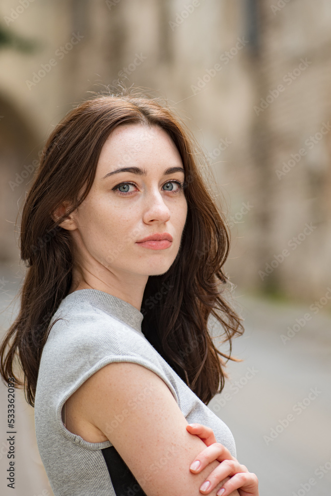 Beautiful Ukrainian girl with red hair, blue eyes and freckles in a short grey summer dress in the city old town with old houses on background, vertical Beautiful Ukrainian girl with red hair, blue eyes and freckles in a short grey summer dress in the city old town with old houses on background, vertical