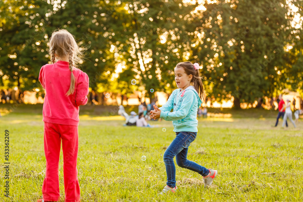 Adorable little girls having fun playing outdoors on summer day Adorable little girls having fun playing outdoors on summer day