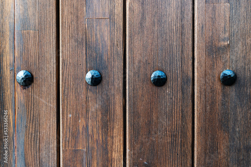 An old grungy, brown, painted, natural wood with grains and big metal nails for background and texture.