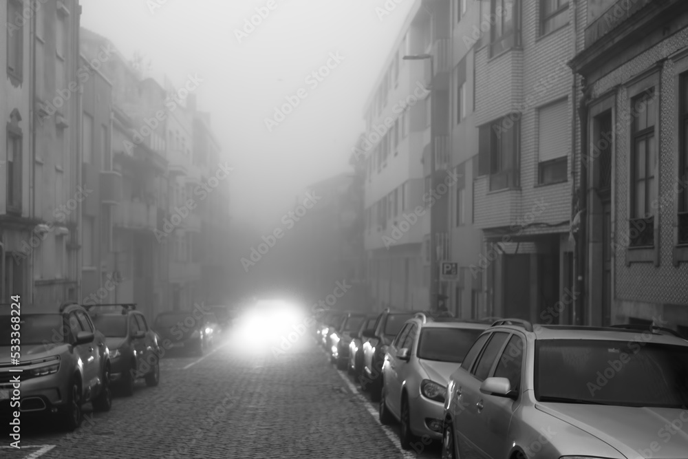 View of a street in the morning in dense fog. Porto, Portugal. Black and white photo.