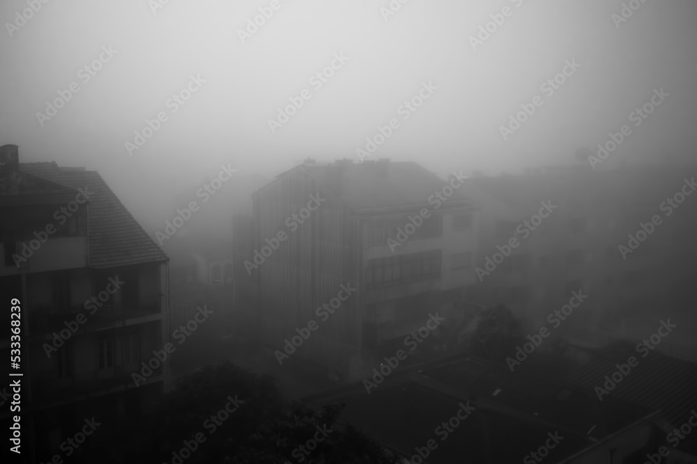 View of the street in the early morning in dense fog. Porto, Portugal. Black and white photo.