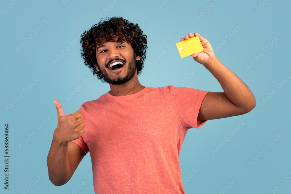 Happy eastern guy showing credit card and thumb up Happy eastern guy showing credit card and thumb up