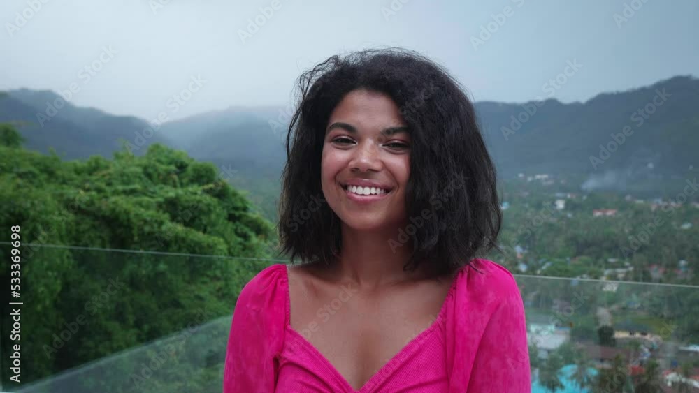African young charming woman standing on a balcony overlooking wonderful tropical asian nature, on a foggy, rainy and overcast day, looking up at the sky with gratitude, as raindrops fall on her face African young charming woman standing on a balcony overlooking wonderful tropical asian nature, on a foggy, rainy and overcast day, looking up at the sky with gratitude, as raindrops fall on her face