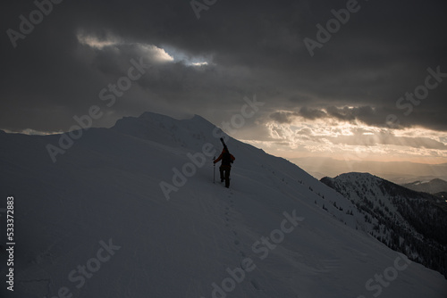 rear view of skier who is walking along snow-covered mountain © fesenko