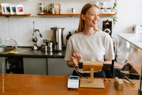 Blonde white barista woman working with tablet computer in cafe