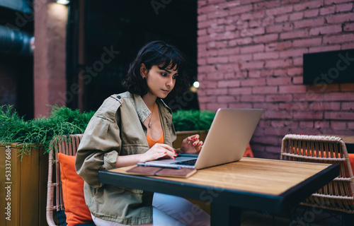 Focused female freelancer working on laptop in cafe