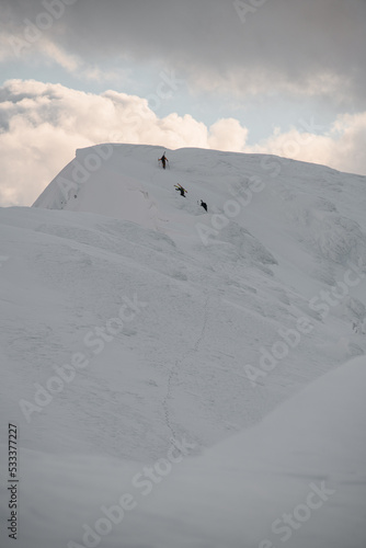 view on mountain slope covered with snow and group of skiers climbing to top