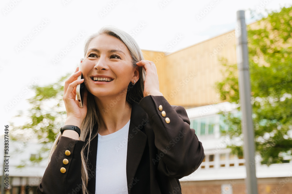 Grey asian woman laughing on cellphone at city street Grey asian woman laughing on cellphone at city street
