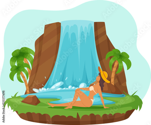 Beautiful young woman in swimsuit relaxing on nature. Pretty girl in straw hat sunbathing on island with waterfall. Girl posing for photo at water flow falling down mountain