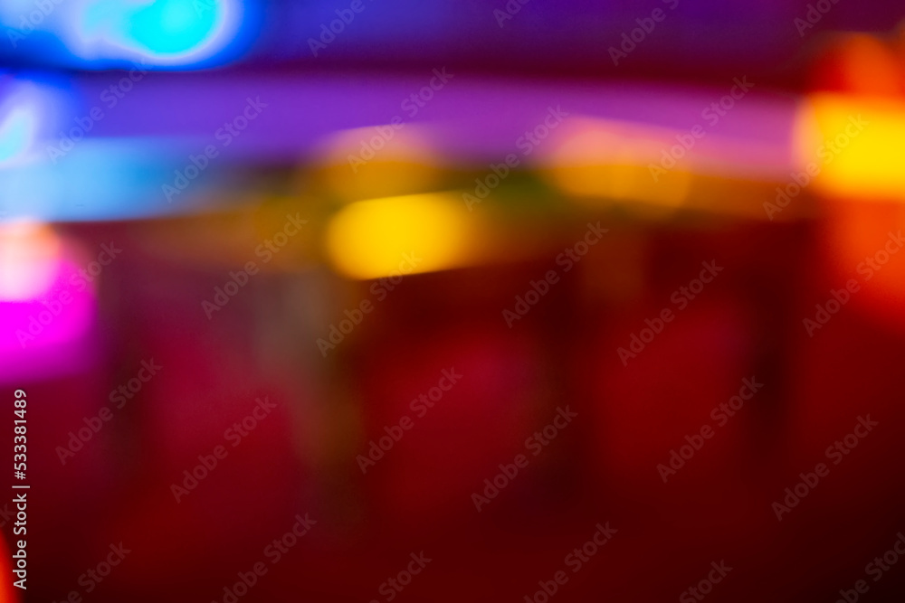 Blurred multicolored background with spots of yellow and purple bokeh. Red background with stripes similar to a night city.