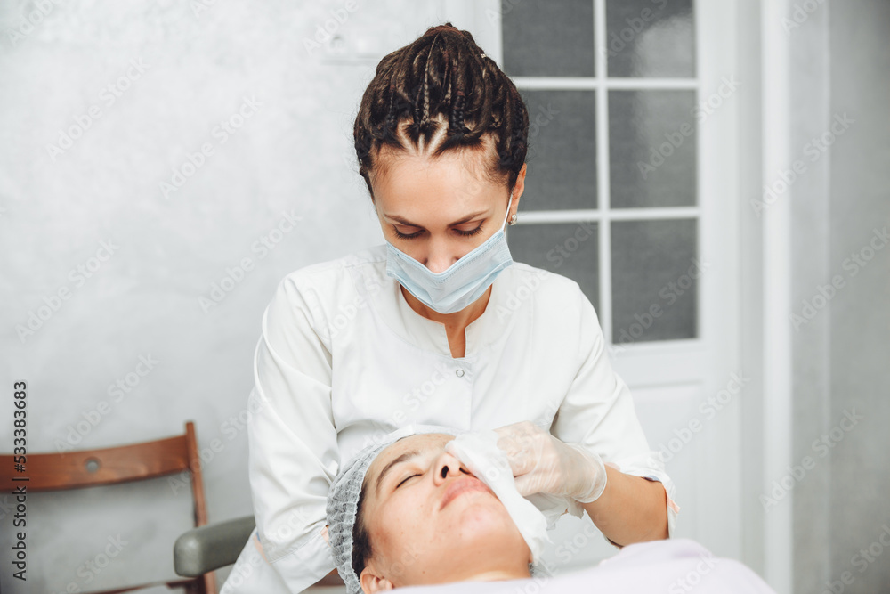 A cosmetologist cleanses the skin of a beauty salon client before the procedure and facial massage. The concept of beauty and health. cosmetology.