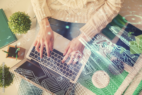 Double exposure of woman hands working on computer and buildings construction hologram drawing. Top View. smart city concept. photo