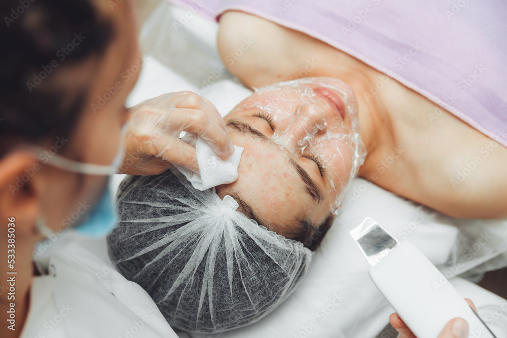 Obraz premium Ultrasonic cosmetic scrubber. Facial cavitation procedure. Salon skin care procedure. Professional hardware peeling. Acne removal. contaminated person