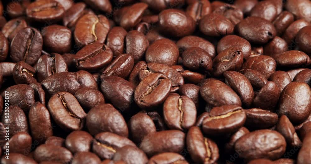 Roasted coffee beans dolly shot. Aromatic coffee beans move slowly. Slide slow motion close-up of whole roasted coffee beans. Roasted coffee beans dolly shot. Aromatic coffee beans move slowly. Slide slow motion close-up of whole roasted coffee beans.