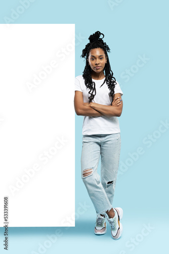 Full length of young woman wearing casual clothes smiling and pointing finger at copyspace isolated over blue background