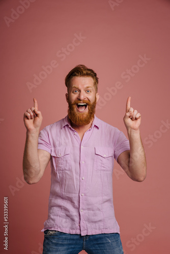 Ginger white man with beard smiling and pointing fingers upward