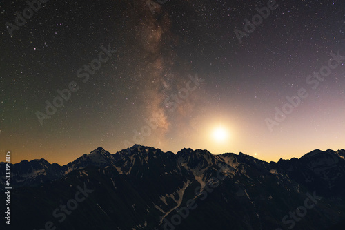 Night landscape. Beautiful snow covered mountains in the starry night with milky way galaxy.