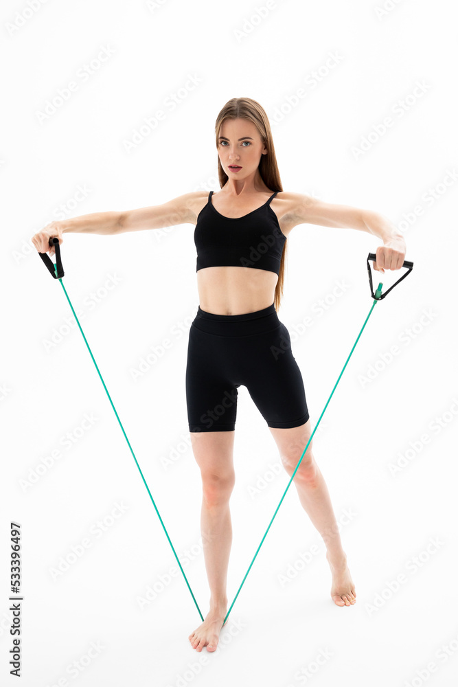 Beautiful girl in sportswear is training with an expander on a white background Beautiful girl in sportswear is training with an expander on a white background