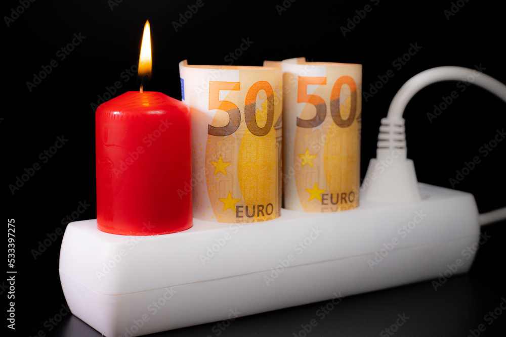 Obraz premium Energy price increase. Burning candles in an electrical extension cord. Increase in energy bill prices.