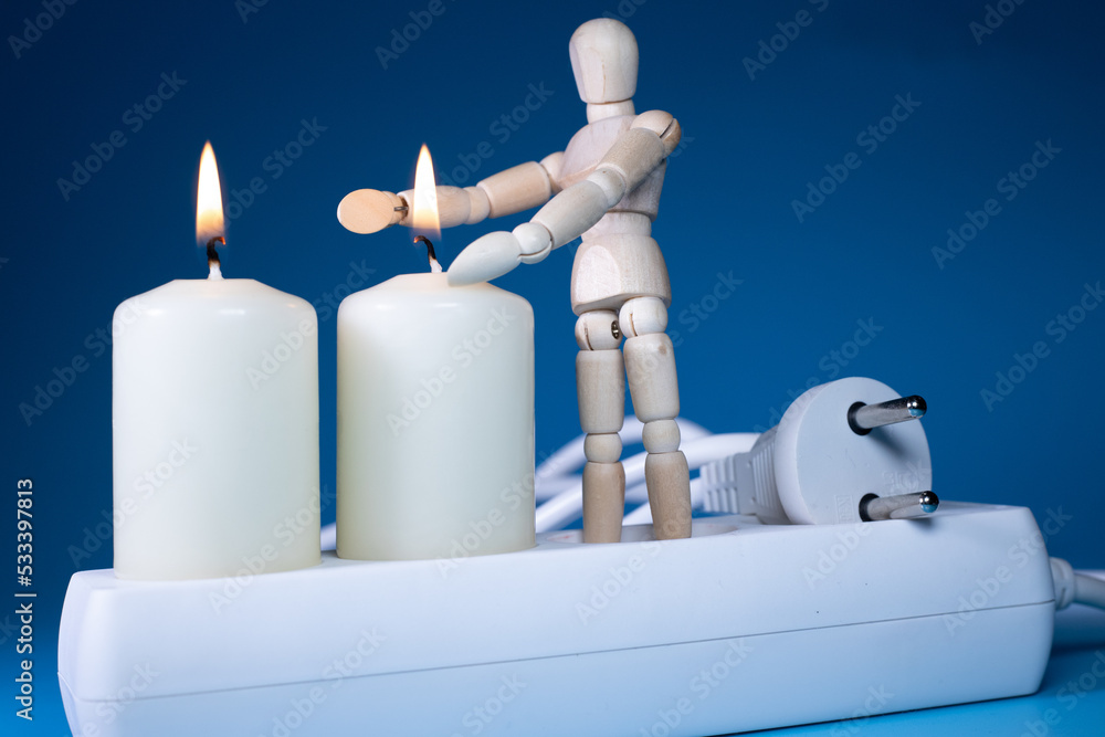Energy price increase. Burning candles with a wooden man warming himself by the candle. Increase in energy bill prices. Energy price increase. Burning candles with a wooden man warming himself by the candle. Increase in energy bill prices.