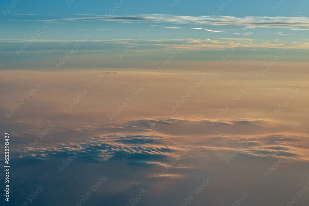 View over the clouds. Cloud cover seen from an airplane. Beautiful sunset sky above clouds.  Beautiful orange and pink sunrise over the clouds