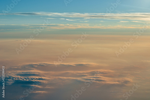 View over the clouds. Cloud cover seen from an airplane. Beautiful sunset sky above clouds. Beautiful orange and pink sunrise over the clouds