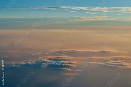 View over the clouds. Cloud cover seen from an airplane. Beautiful sunset sky above clouds. Beautiful orange and pink sunrise over the clouds