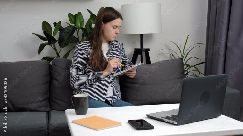 Close up of focused young woman sit on couch and tears up a sheet of notebook because of bad idea. Freelance girl trouble of work from employee make fail work finance report, small business, startup
