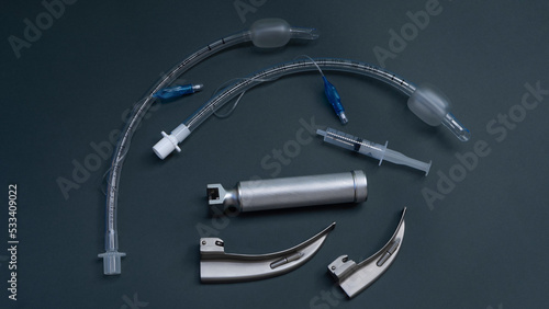 tracheal intubation kit: laryngoscope, several laryngoscope blades and several endotracheal tubes, a syringe to inflate the cuff of the tube. on a dark background, close-up photo