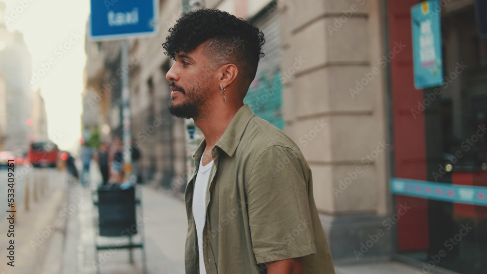 Young man with beard dressed in an olive-colored shirt crosses the road at pedestrian crossing Young man with beard dressed in an olive-colored shirt crosses the road at pedestrian crossing