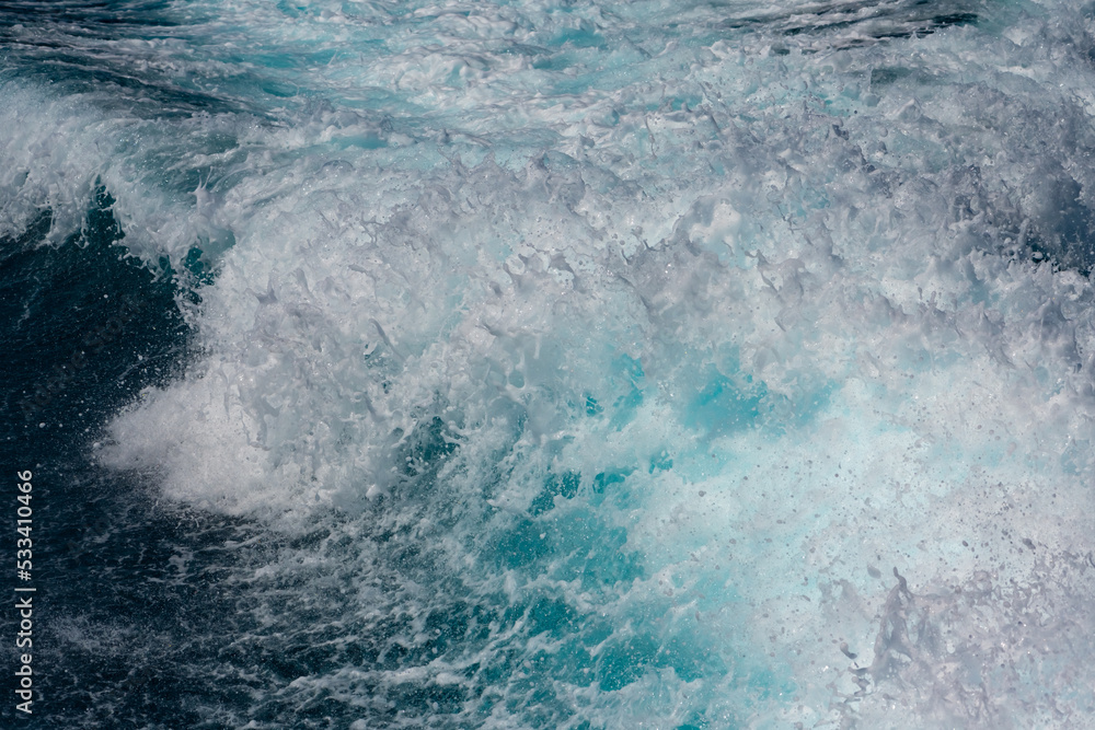 Obraz premium Breaking wave with white heads of foam drops, spray and turquoise water color. Frozen motion with many details of sprinkles, spatter and splaches, high contrast on a sunny day in Mediterranean Sea.