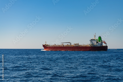 Oil or chemical tanker on a sunny day on the mediterranean sea. Red vessel on its way to next port carrying liquids to supply industry with energy or resources. International ship traffic in Italy.