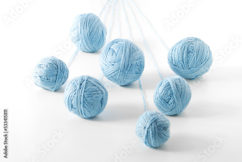 unwound threads from balls of blue yarn, on an isolated white background