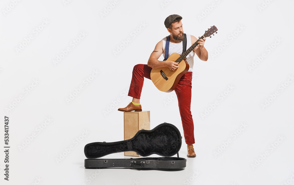 Fototapeta premium Expressive musician wearing retro style clothes playing guitar like rockstar isolated on white background. Retro style, vintage fashion, music, art