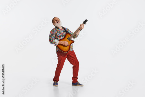 Expressive musician wearing retro style clothes playing guitar like rockstar isolated on white background. Retro style, vintage fashion, music, art