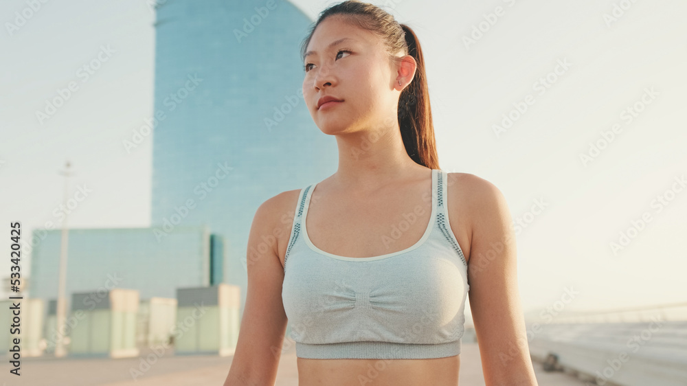 Asian girl in sports top walking outside at morning time Asian girl in sports top walking outside at morning time
