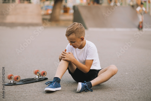 Quadro em tela Kid boy teenager in a special area in skatepark fell and hurt his knee