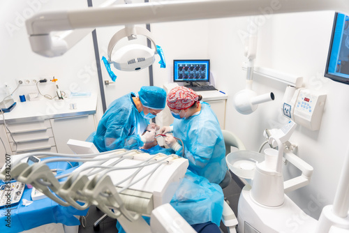 Dental clinic, dentists in blue suits performing an implant, view from above of the operation
