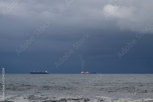 Ships on the horizon against rainy sky