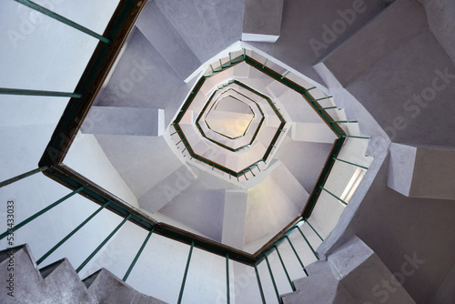 An upward view of a staircase or stairwell with a railing