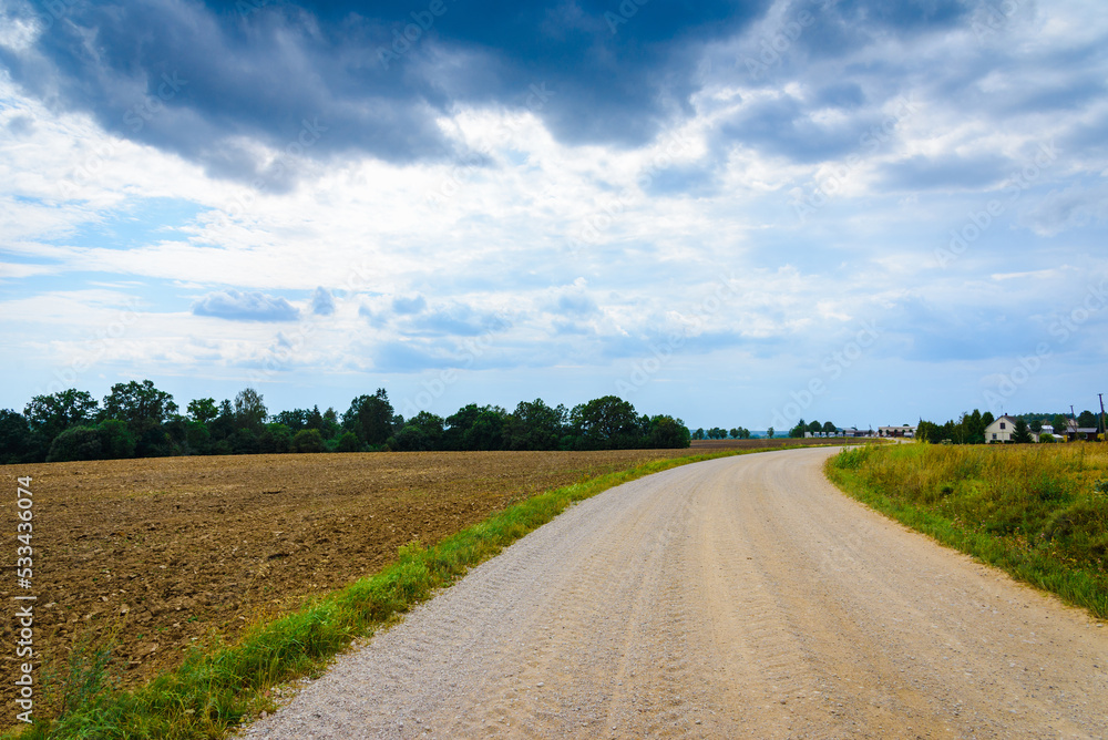 Obraz premium Country road and green trees farmland landscape in a summer season.
