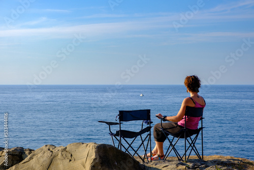 Ragazza si rilassa guardando l'Oceano nei pressi di Zumaia, Paesi Baschi, Golfo di Biscaglia, Mar Cantabrico, Spagna photo