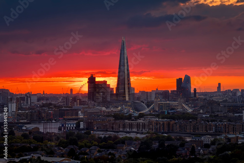 Elevated view of the London skyline during a cloudy sunset with intense red colors and sunlight during autmn time, England © moofushi