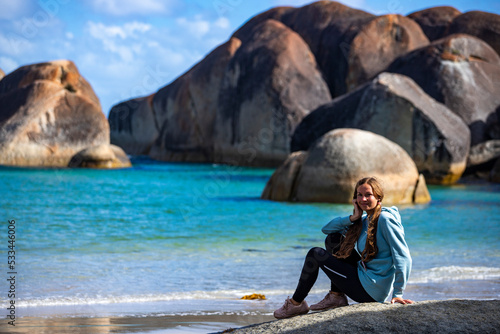girl with ponytails sits on rocks on paradise beach in western australia, famous elephant rocks