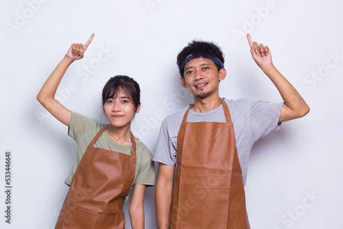 Asian couple barista waiter wears apron pointing with fingers to different directions isolated on white background photo