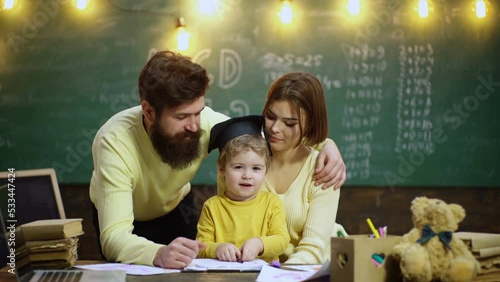 Young family studying and education. Young mother father and little preschooler boy sit at table drawing together, playing, painting pictures in notebook, early development. photo